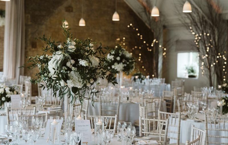 Tall vases of flowers decorate the dining tables. Photography by David Hughes Photography