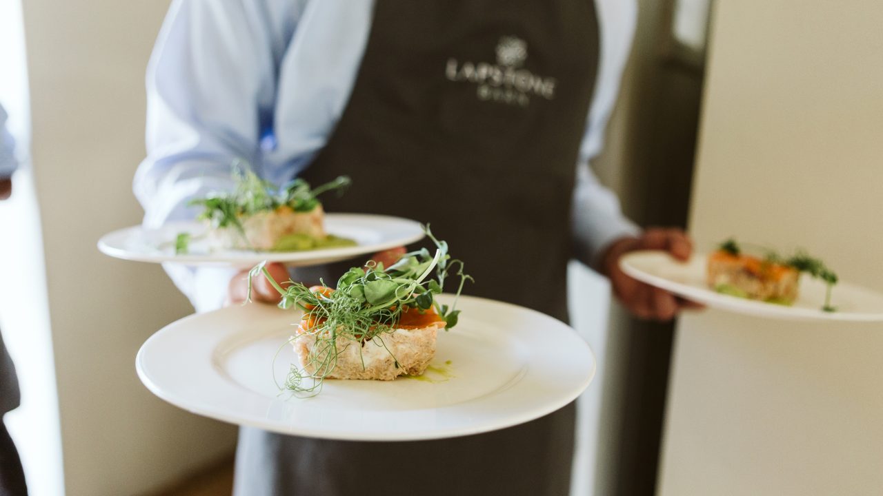Waiter carrying plates of food to guests