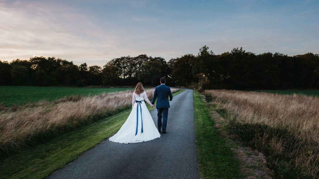 Bride and groom walking down the drive together. Image by Tanli Joy Photography