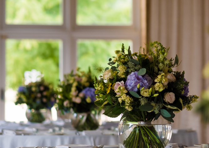 Tables laid for the wedding breakfast with floral arrangements by The Broadway Florist