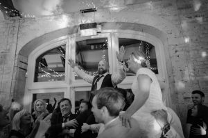 Bride and groom on friend's shoulders on the dance floor