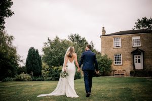 Bride and groom walking hand and hand in the garden