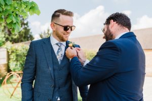 Groomsmen helping the groom put on his buttonhole