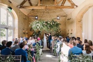 Floral bars hanging over rows of tables laid for the wedding breakfast