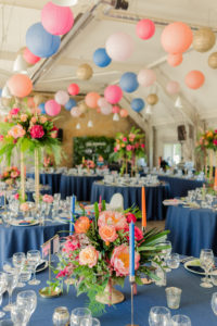 Colourful paper lanterns hanging over round tables decorated with bright neon colours